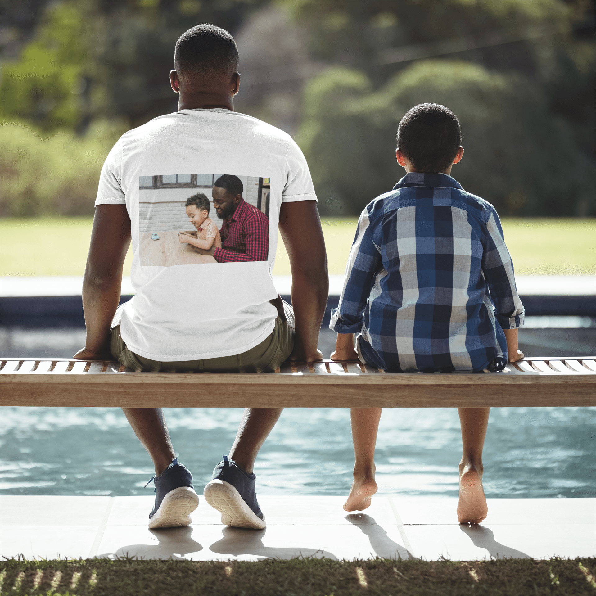 Pai e filho sentados de costas, usando camiseta personalizada